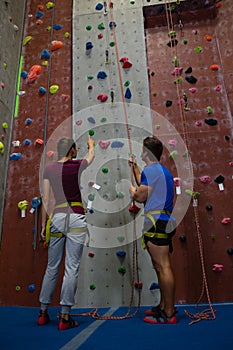 Low angle view of male trainer guiding woman in climbing wall