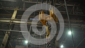 Low angle view of manual worker operating crane lifting sheet metal in industry. Crane in the factory lifts metal sheets