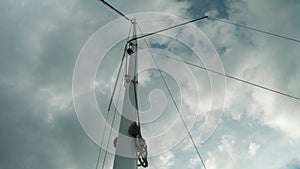 Low angle view of mast of yacht sailing on river Volga. Dramatic view of white clouds at background of cords and mast.