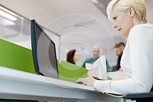 Low angle view of mature businesswoman using computer with colleagues in background at office