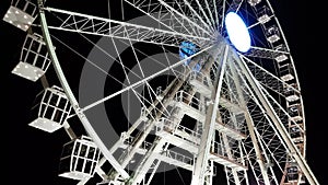 Low angle view of metallic ferris wheel illuminated against night sky