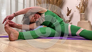 Low angle view middle-aged woman stretching doing fitness indoors