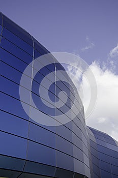 Low angle view of a modern building with blue glass windows under sunlight and a blue sky