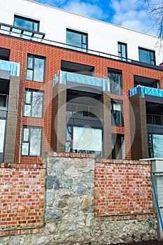 Low angle view on modern residential brick apartment building exterior with large windows. Modern Apartment Complex Under