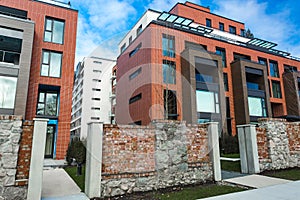 Low angle view on modern residential brick apartment building exterior with large windows. Modern Apartment Complex Under