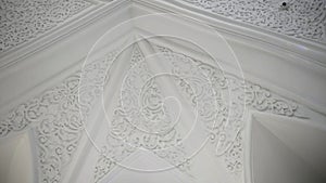 Low angle view of mosque interior. Scene. Ceiling inside majestic temple, carved ornament on white walls and ceiling.