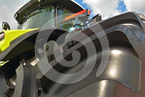 Low angle view of a new farm tractor with a close-up of an agricultural tractor tire