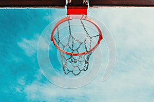 Low-angle view of an outdoor basketball hoop with a chain net