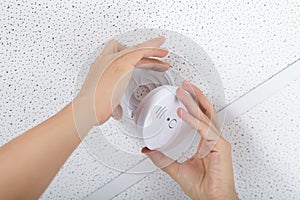 Person`s Hand Installing Smoke Detector On Ceiling photo