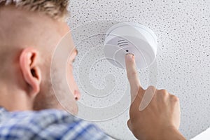 Person`s Hand Installing Smoke Detector On Ceiling photo