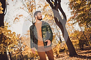 Low angle view photo of attractive positive guy go outdoors autumn park look wear season outercoat