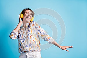 Low angle view photo of happy joyful young woman listen good music headphones dance isolated on blue color background