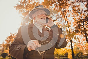 Low angle view photo of retired funny white hair grandpa walk desert park stick speaking telephone daughter son family