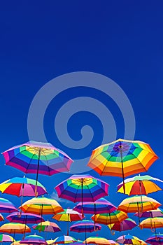 Low Angle View Of Rainbow Colored Umbrellas Hanging On The Background Of A Blue Sky