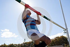 Low angle view of rugby player exercising on goal post against sky