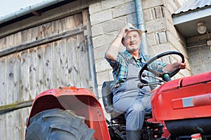 Low angle view of senior farmer wearing hat and driving tractor