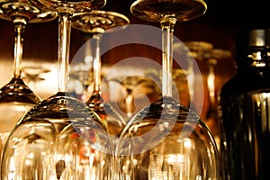Low angle view on shiny isolated wine glasses in wooden retro cupboard with black alcohol bottle