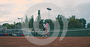 Low angle view in slow-motion of a young female tennis player preparing to serve a tennis match. A woman athlete is