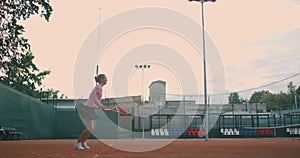 Low angle view in slow-motion of a young female tennis player preparing to serve a tennis match. A woman athlete is