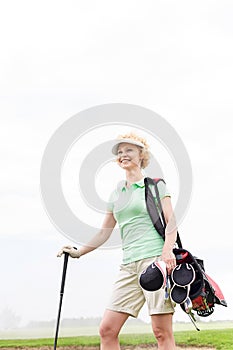 Low angle view of smiling female golfer standing against clear sky