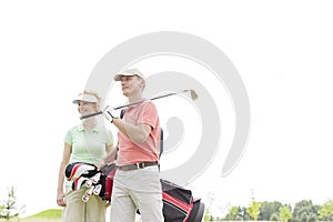 Low angle view of smiling golfers standing against clear sky