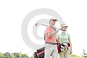 Low angle view of smiling golfers standing against clear sky