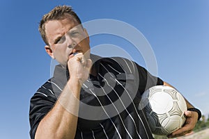 Low angle view of soccer referee showing yellow card against blue sky