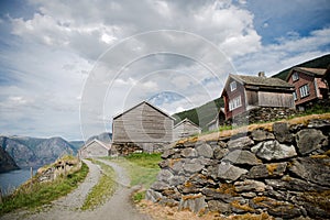 low angle view of stone wall rural road and wooden houses at majestic Aurlandsfjord Flam