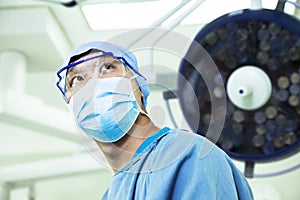 Low angle view of surgeon wearing a surgical mask and glasses in the operating room