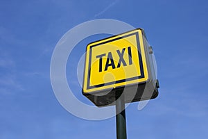 Low angle view of taxi sign against blue sky