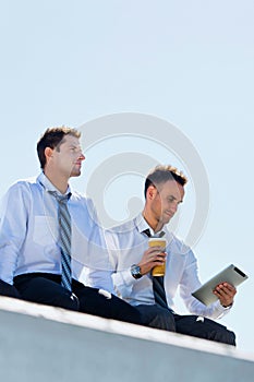 Low angle view of thoughtful mature businessmen sitting and relaxing on rooftop during break in office