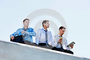 Low angle view of thoughtful mature businessmen sitting and relaxing on rooftop during break in office