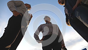 Low angle view of three business men standing outdoor near office and talking. Businessmen meet and speaking outside in