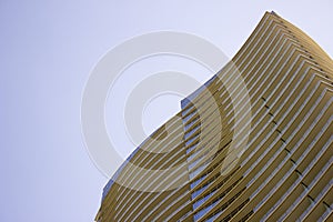 Low angle view of the top part of a modern corporate building with yellowish overhangs in each floor.