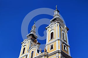 Low-angle view of towers of sunlit Baroque church in Hungary