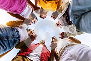 Low angle view of united group of young people in circle holding hands