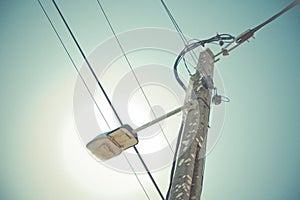 Low angle view of utility pole with electrical wires and a streetlight against a clear sky