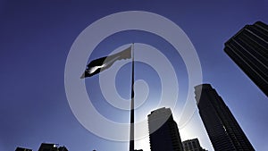 Low angle view of a waving flag against blue sky. Action. Dubai, UAE, architecture and waving flag.