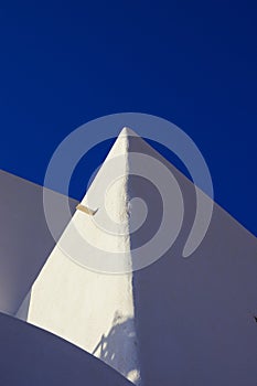 A low angle view of a white cycladic house against the blue sky