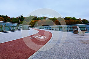 Low-angle view of winding red color bike lane with white bicycle sign on the New Pedestrian Bridge in Kyiv, Ukraine