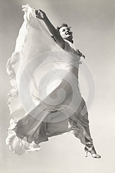 Low angle view of woman in gown jumping in mid-air