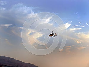 Low angle view of yellow color Gyrocopter flying in the blue sky and dramatic clouds, fun fly, aero sports, skydive, Roto craft, photo