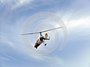 Low angle view of yellow color Gyrocopter flying in the blue sky and dramatic clouds, fun fly, aero sports, skydive, Roto craft, photo