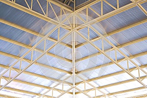 Low angle view of yellow metal building roof structure with heat insulation in construction site