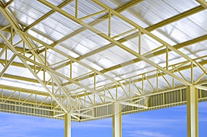 Low angle view of yellow metal building roof structure with heat insulations in construction site area