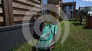 Low angle view of young man mowing lawn at home. Gimbal movement backward