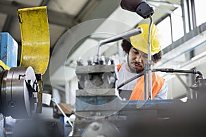 Low angle view of young manual worker working on machinery in metal industry