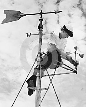 Low angle view of a young woman mending a weather vane