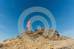 Low angle of a woman standing on top of the castle of Melhor, Portugal against a blue sky photo