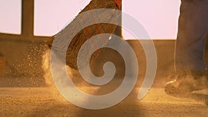 LOW ANGLE: Worker sweeps the dusty floor after long day at the construction site